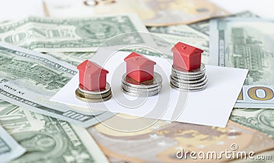 Minature houses resting on pound coin stacks Stock Photo