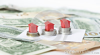 Minature houses resting on pound coin stacks, mortgage and real estate investment Stock Photo