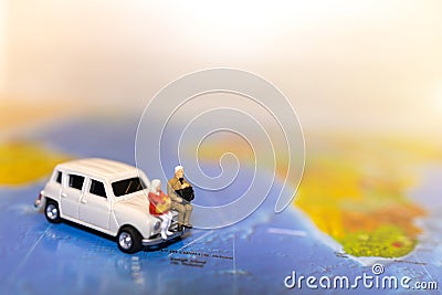 Minature people: traveling with a backpack sitting on car and world map. Stock Photo