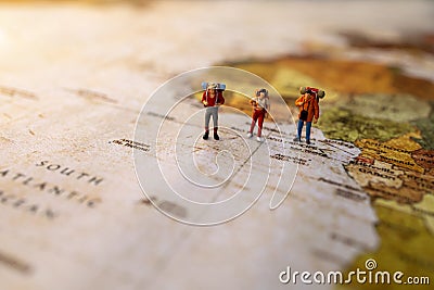 Minature people: traveling with a backpack standing on vintage world map, Travel and vacation concept Stock Photo