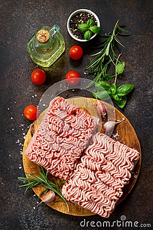 Minced beef and pork on a cutting board, raw meat and various spices on a stone or slate background. Stock Photo