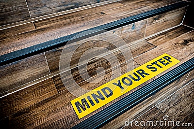 Mind your step sticker sign pasted on wooden stair. Warnings, abstract, or indoor architecture concept Stock Photo