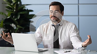 Mindful calm millennial businessman meditating at workplace. Stock Photo