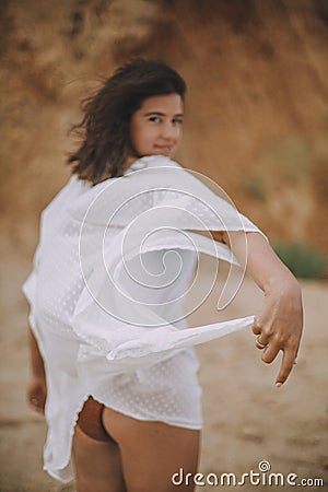 Mindfulness and relaxation. Joyful boho girl in white summer dress walking on beach. Hands with dress closeup. Carefree young Stock Photo