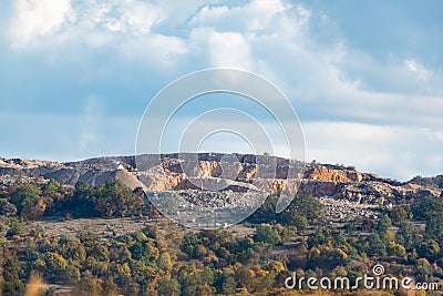 Mine dig machinery on a hill in the distance telephoto far away autumn vibrant scene blue sky trees mountain nature Stock Photo