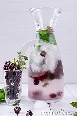 Mineral infused water with blackberry, ice, herb and mint leaves on white background, homemade detox soda Stock Photo