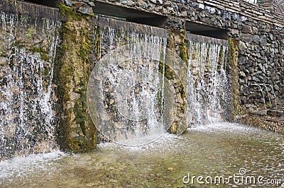Mineral spring. Stream in the SPA. Curative water. Resort. Waterfalls. Summer. Clear and fresh water on the stone wall Stock Photo