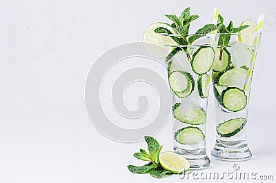 Mineral water with slices cucumber, ice, lime, mint on white wood table with copy space. Stock Photo