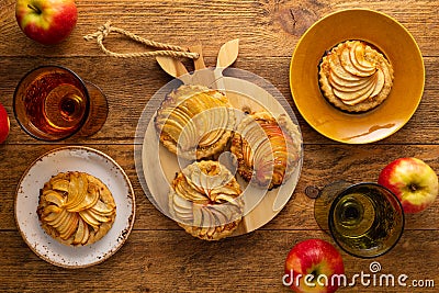 Mini Apple pie tartlets with walnut on wooden table. Delicious dessert for autumn winter dinner.Top view Stock Photo