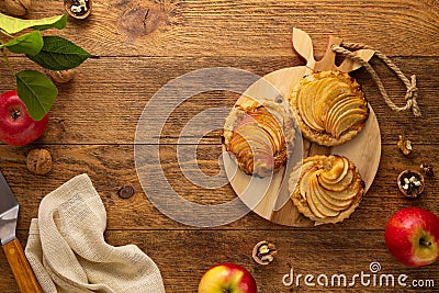 Mini Apple pie tartlets with walnut on wooden table. Delicious dessert for autumn winter dinner.Top view Stock Photo