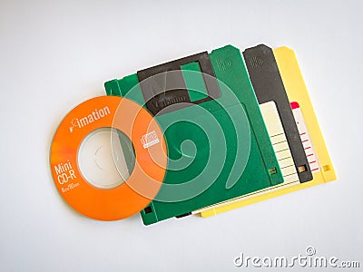 Mini CDs stacked on floppy disks, objects isolated on a white background, the evolution of technology Editorial Stock Photo