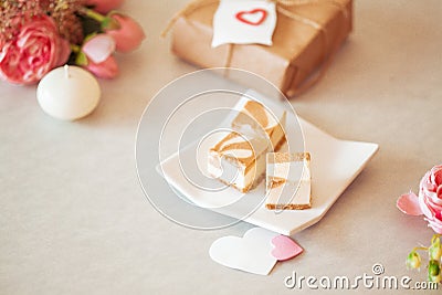 Mini cheese cake platter - caramel cheese cake on white plate with pink peomies and brown paper wrapped present Stock Photo
