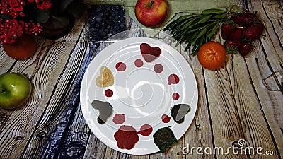 Mini colorful pancakes placed arround a white plate on a wooden background surrounded by fruits Stock Photo