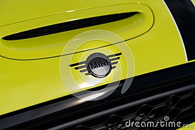 Mini Cooper brand badge placed on bright yellow hood with black stripe of new sports automobile. Luxury details of Editorial Stock Photo