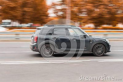 Mini Cooper on the city road. Fast moving car on Moscow streets. Vehicle driving along the street in city with blurred autumn Editorial Stock Photo