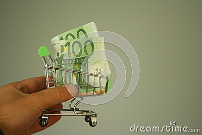 mini dummy shopping cart in human hand with paper euro banknotes as a concept for online shopping, saving, business and making mon Stock Photo