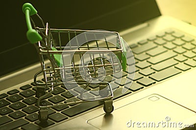 A mini dummy shopping trolley on a lapptop keyboard as a concept for online shopping, saving, business and making money Stock Photo