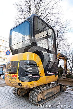 Mini excavator on the construction site. Replacement of paving slabs and repair of roads in the city. Crawler excavator with a Editorial Stock Photo