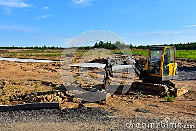 Mini excavator digg trench to lay cables concrete curbs and paving slabs at construction site. Backhoe on earthwork/roadworks Stock Photo
