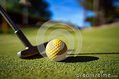 Mini Golf yellow ball with a bat at sunset Stock Photo
