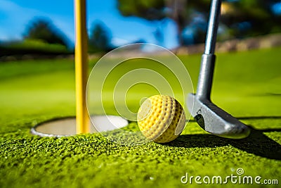 Mini Golf yellow ball on green grass at sunset Stock Photo