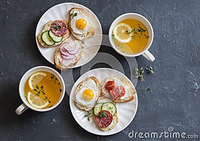Mini sandwiches with cream cheese, vegetables, quail eggs, salami and green tea with lemon and thyme. Sandwiches with cheese, cucu Stock Photo
