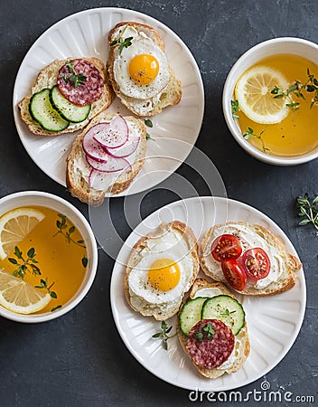 Mini sandwiches with cream cheese, vegetables, quail eggs, salami and green tea with lemon and thyme. Sandwiches with cheese, cucu Stock Photo