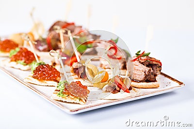 Mini snacks tapas with caviar and meat on white plate Stock Photo