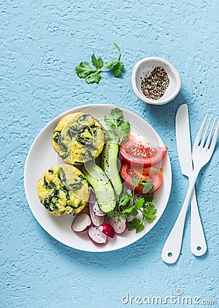 Mini spinach cheddar frittata and vegetables salad on blue background, top view. Breakfast, snack, appetizers Stock Photo