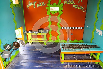 A miniature aqua blue house with green and orange trim in the garden with pots and pans and wrenches inside Stock Photo