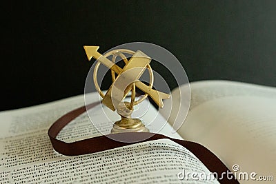 A miniature astrolabe figurine on pages of a book. Stock Photo