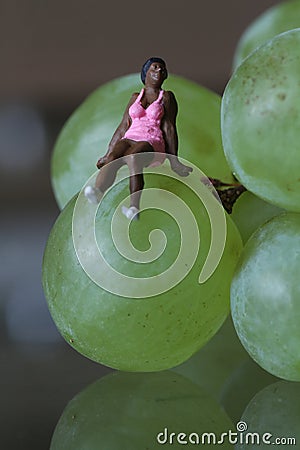 Miniature of a black woman sitting on the grapes Stock Photo