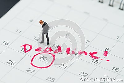 Miniature business man standing on desktop calendar with red circle on important date with handwriting deadline, goal or target Stock Photo