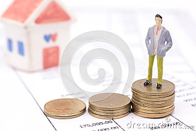 Miniature businessman and stack coins on statement and the house Stock Photo