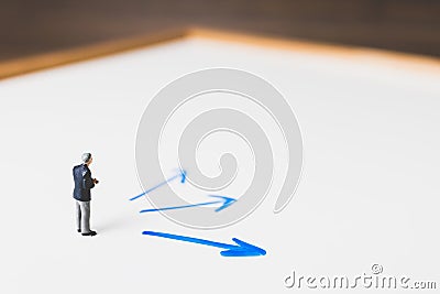 Miniature Businessman standing on arrow pathway Stock Photo