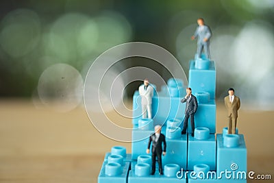 Miniature businessman standing on blue block Stock Photo