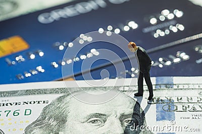 Miniature businessman in suit standing and thinking on US dallar banknote and credit card using as online shopping, debt, money Stock Photo