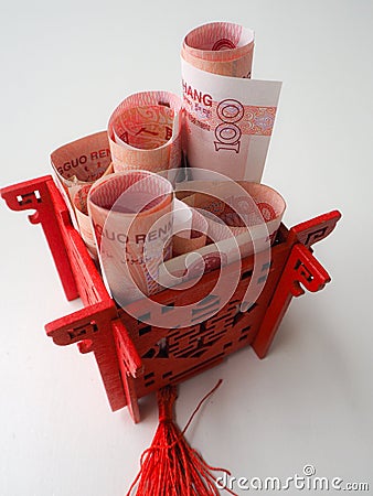 Miniature Chinese pavilion in bright red filled with Chinese 100 renminbi banknotes against a white background Stock Photo