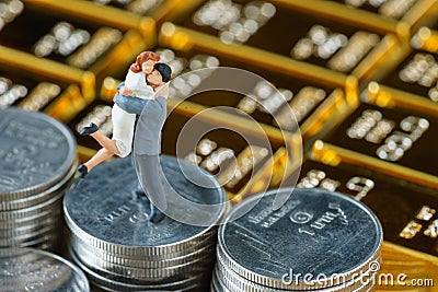 Miniature couple figure standing on stack of coins with shiny go Stock Photo