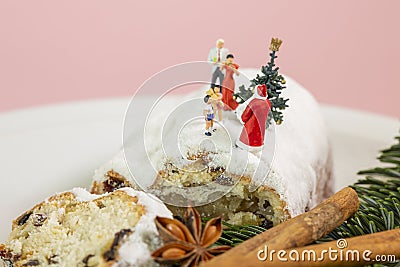 A miniature family is celebrating christmas on top of an powdered fruit cake Stock Photo