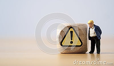 Miniature figure of senior engineer standing and see at warning exclamation caution sign for notification maintenance and Stock Photo