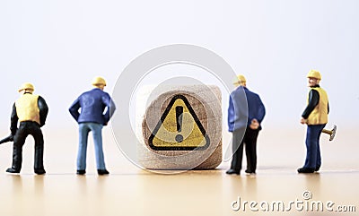 Miniature figure of senior engineer standing and see at warning exclamation caution sign for notification maintenance and Stock Photo