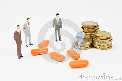 A miniature figurine of a man sits on coins, next to him are pills and figurines of people. Stock Photo