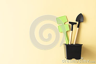 Miniature gardening tools and inscription board in flowerpot on beige background Stock Photo