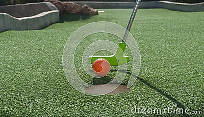 Miniature Golf Putter Tapping Ball into Hole Stock Photo