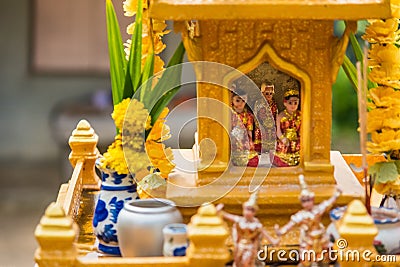 Miniature guardian spirit house. Small buddhist temple shrine, colorful flower garlands. San phra phum erected to bring fortune. Stock Photo