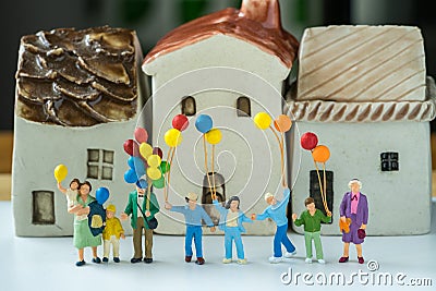 Miniature happy family holding balloons with ceramic house as pr Stock Photo