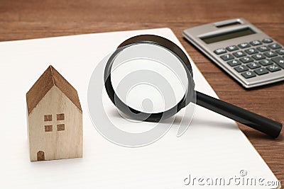 Miniature house, magnifying glass, calculator on blank notebook. Stock Photo