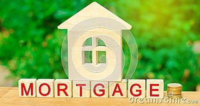 Miniature house and money. Wooden blocks and the inscription `mortgage`. credit for property / apartment. Business loans for real Stock Photo
