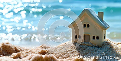 A miniature house on the sand against the backdrop of the sea or ocean. Travel vacation rental concept. Resort property Stock Photo